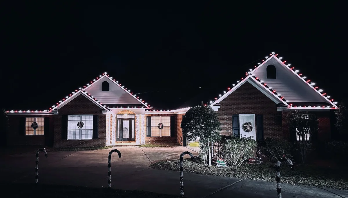 Red and white Christmas lights on a brick home in Tallahassee with lit wreaths and candy cane path lights
