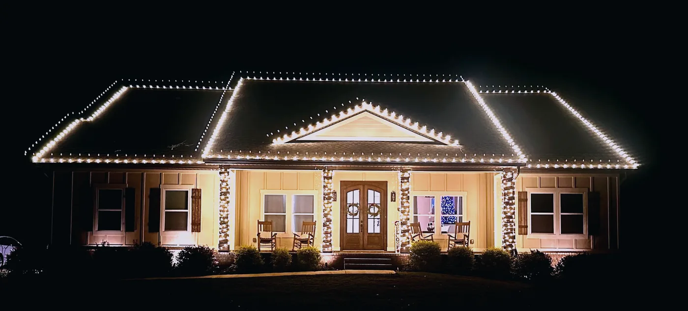 Warm white roofline with wrapped columns and lit wreaths on a Tallahassee home
